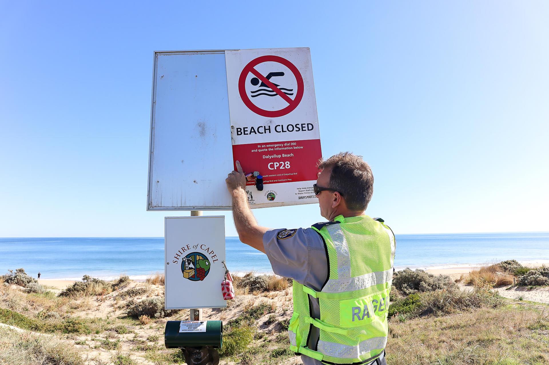 Ranger changing beach safety signs at beach