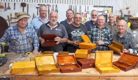 Group of men Infront of wooden boxes in workshop