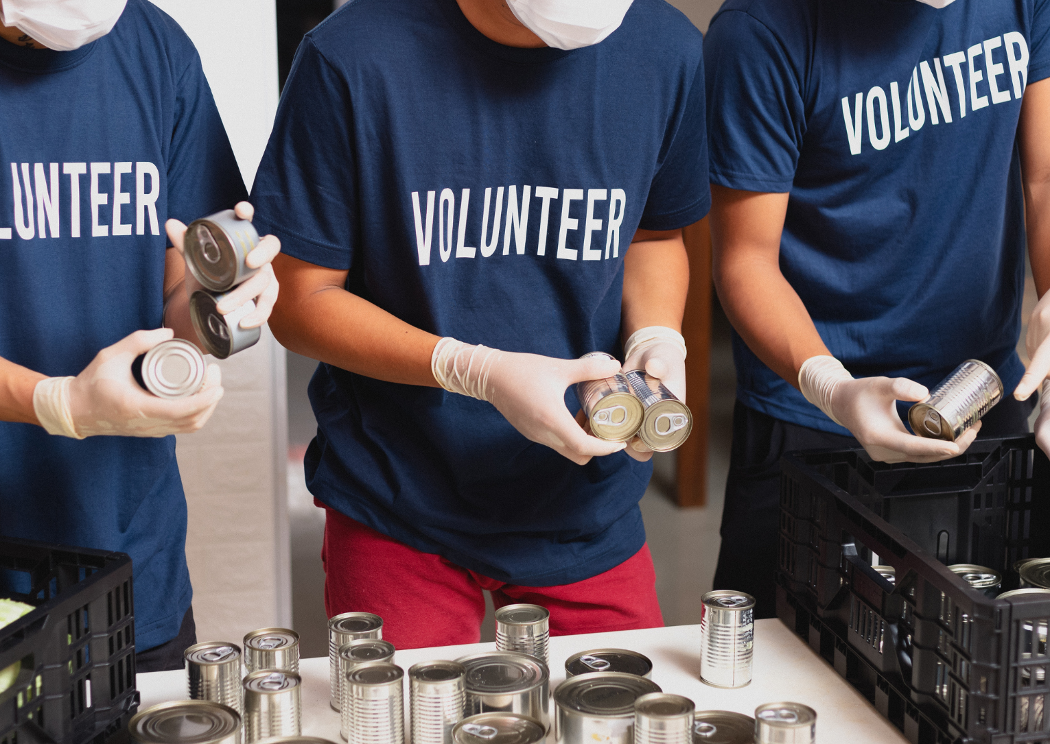 three people with volunteer shirts sorting cans