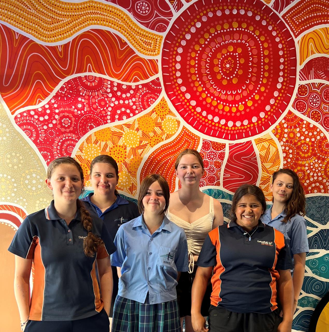 group of children in front of aboriginal mural