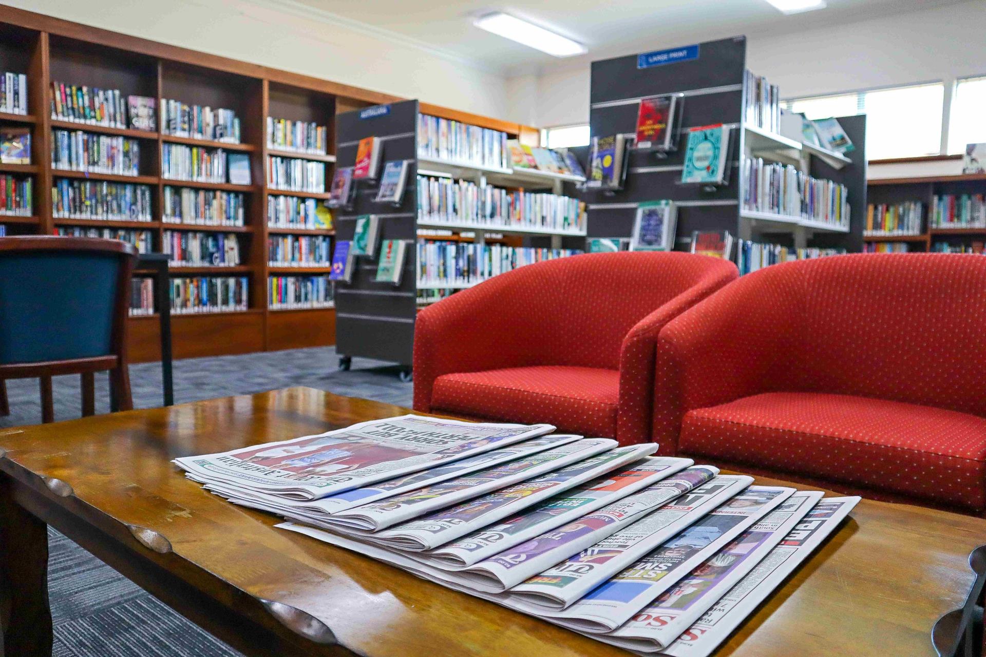 Newspapers with chairs in background in library
