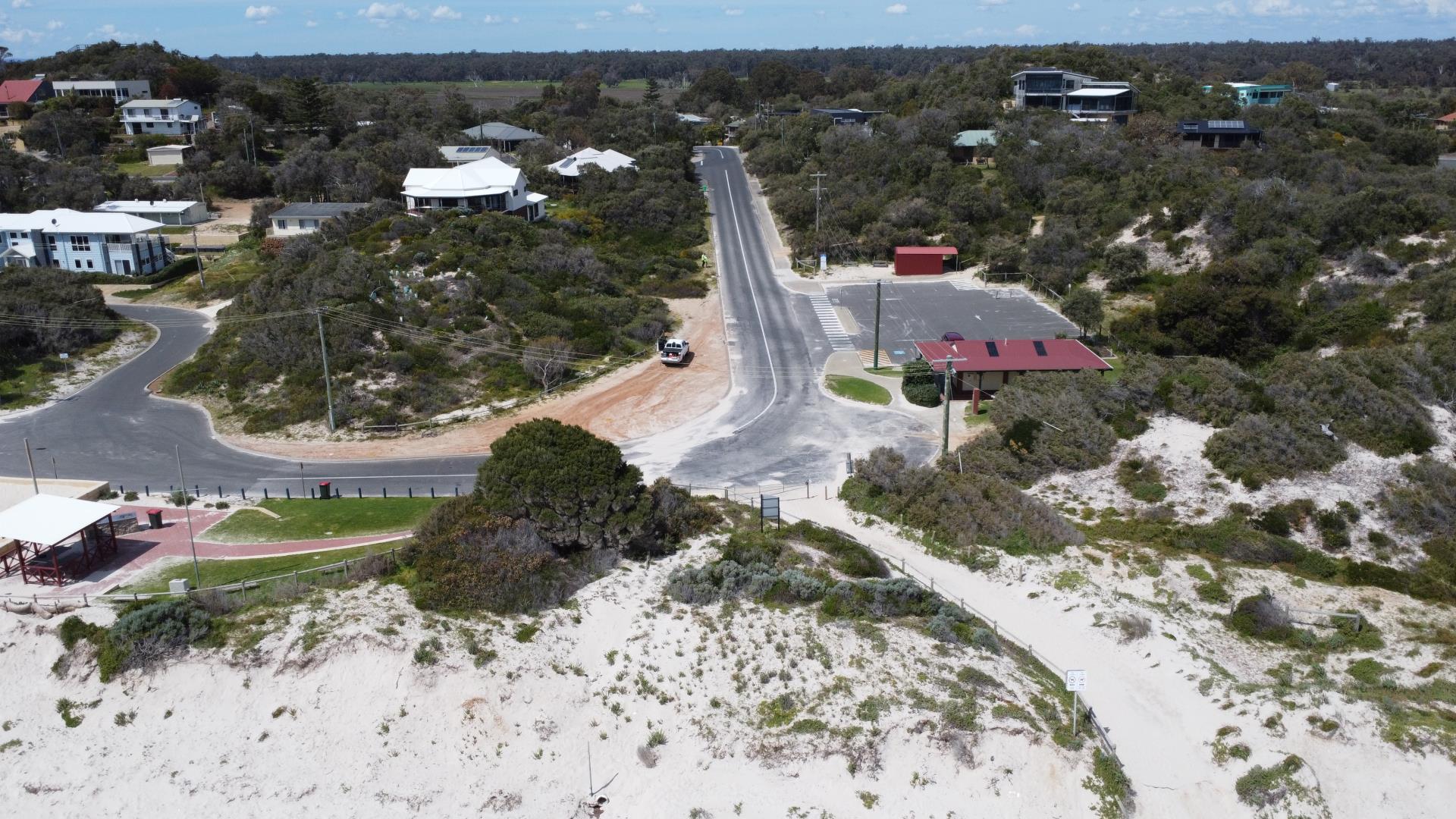 aerial photo of beach community, carpark and hill