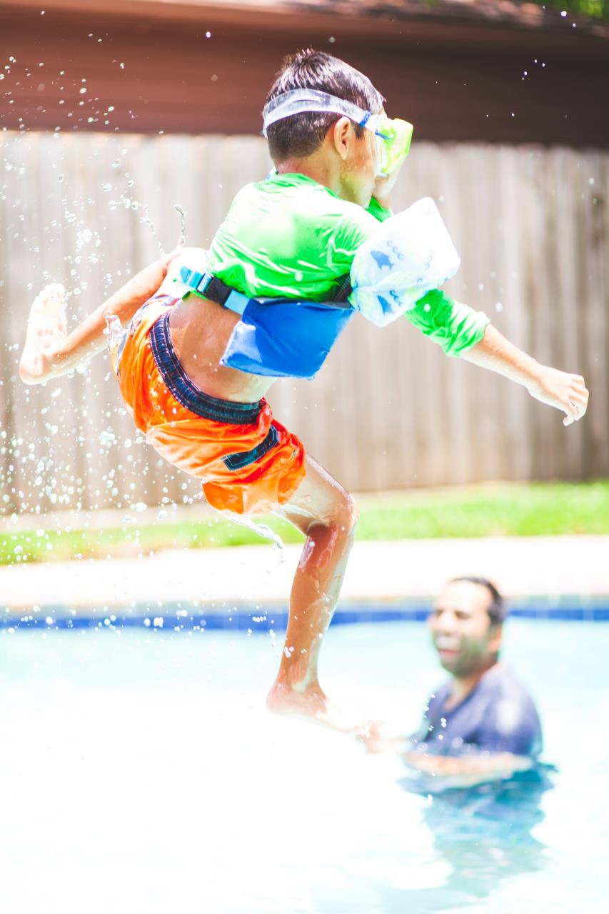Child jumping into a backyard pool