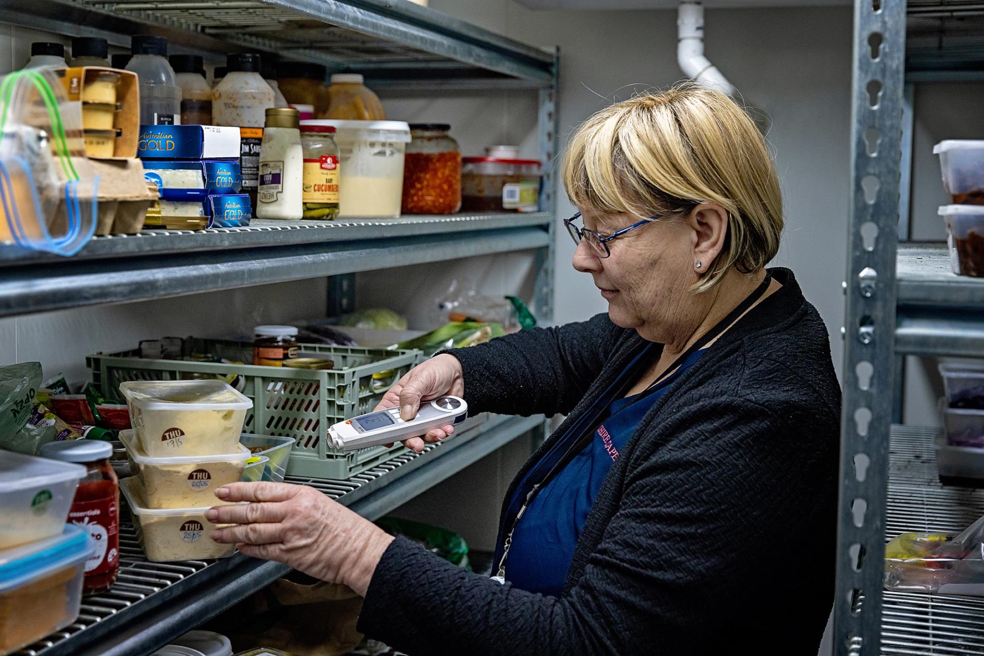 Shire staff measuring temperature of food in fridge.