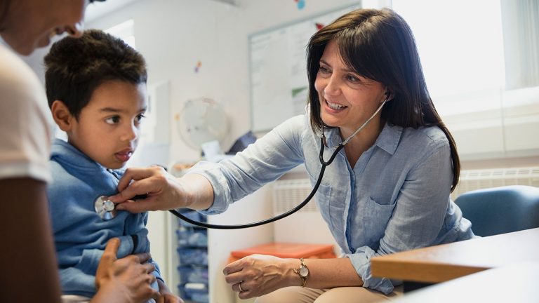 Female doctor listening to young boys heart with stethescope