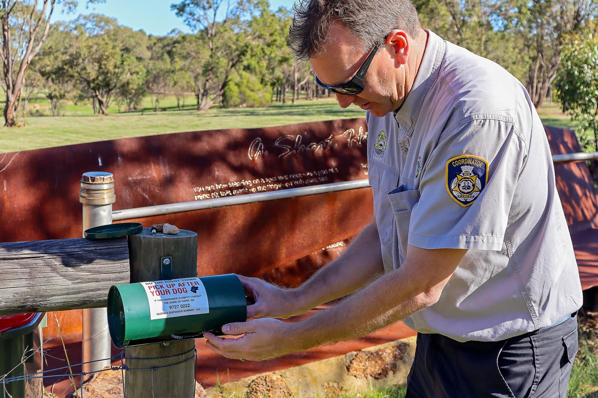 Man refilling a dog poo bag dispenser 