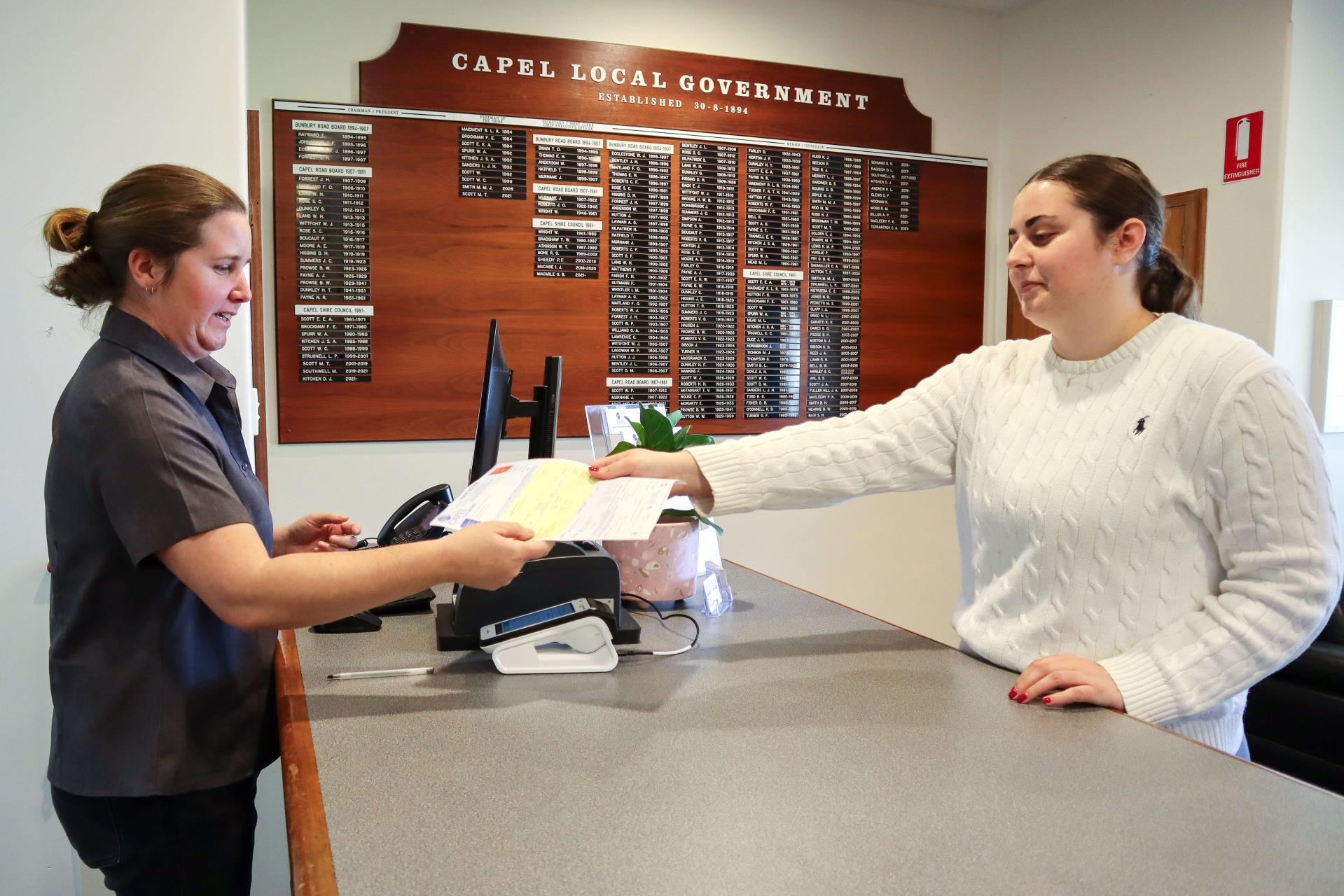 Shire officer handing receipt to member of public in shire office